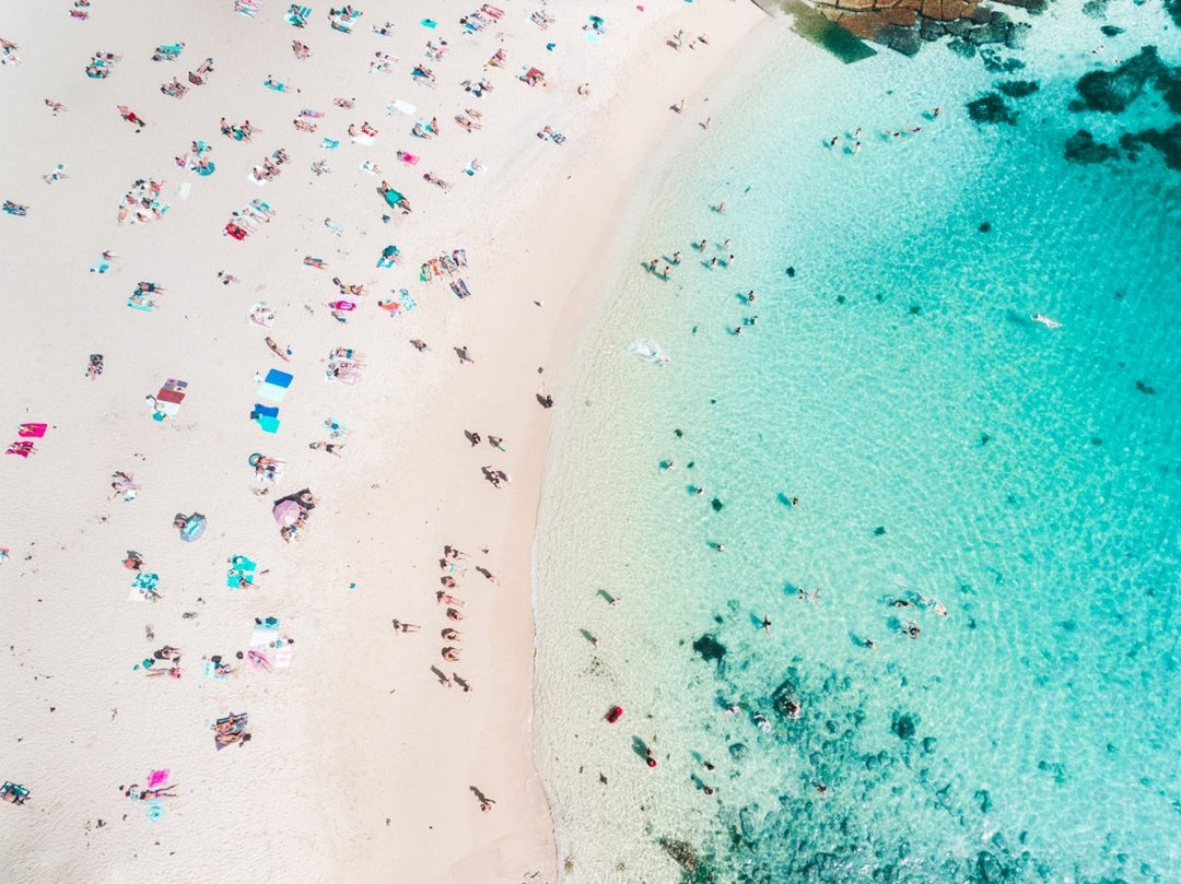 Summers day at Shelly Beach with people tanning and swimming in blue water in Sydney