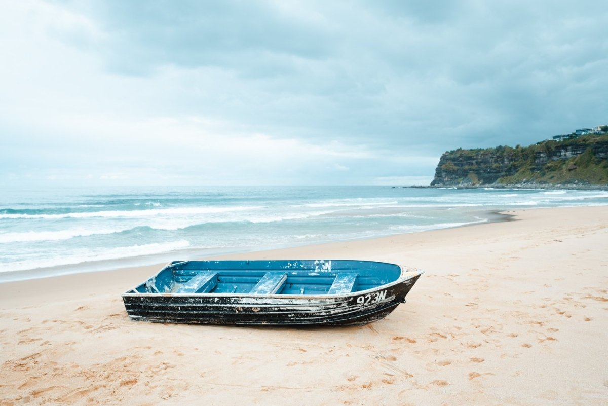 Stranded blue boat on northern beaches on cloudy day