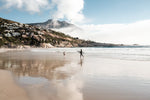 Surfer walking towards a kid on Llandudno Beach in Cape Town