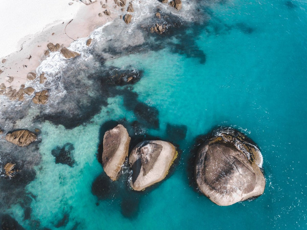 Aerial of three big boulders in blue Atlantic Sea in Clifton Cape Town