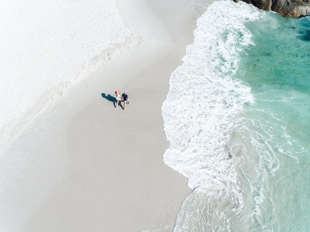 Aerial of a couple holding hands walking along Clifton Beach in Cape Town