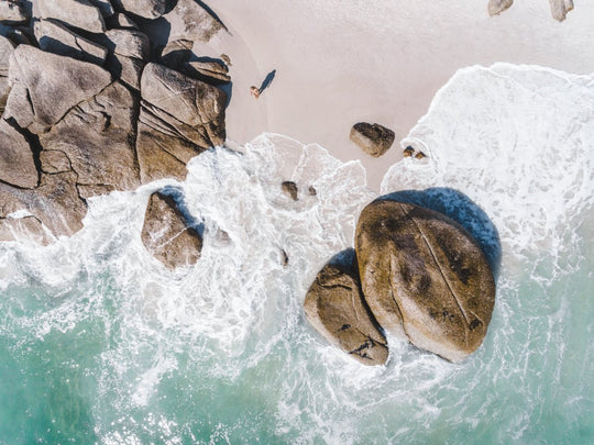 Girl standing among boulders on Clifton beach from above