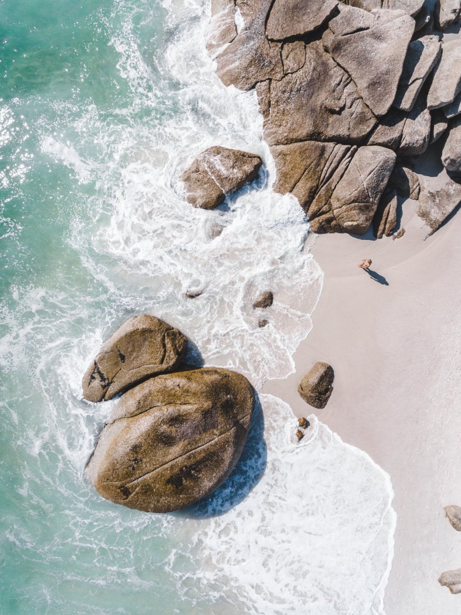 Girl standing among boulders on Clifton beach from above