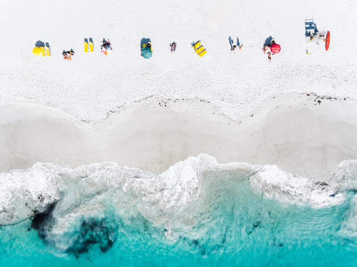 Aerial of colorful towels and umbrellas along blue sea on Clifton Beach Cape Town