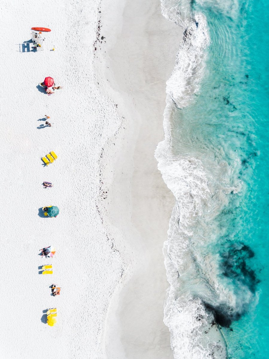 Aerial of colorful towels and umbrellas along blue sea on Clifton Beach Cape Town