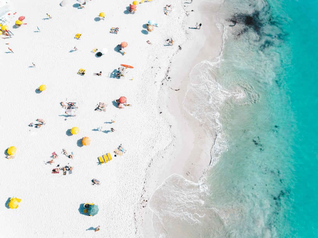 Colorful umbrellas, towels and people along white sand of Clifton Beach Cape Town