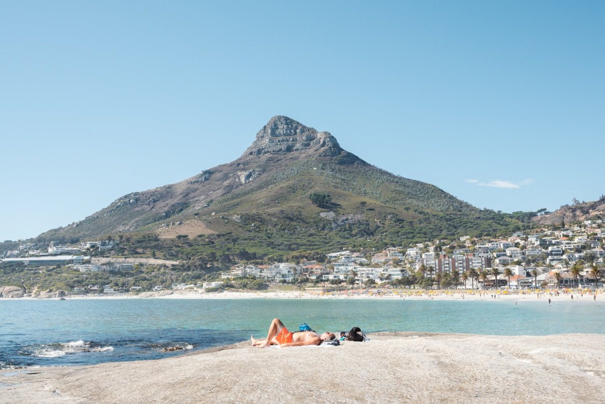 Old man lying on rock at Camps Bay beach below lions head