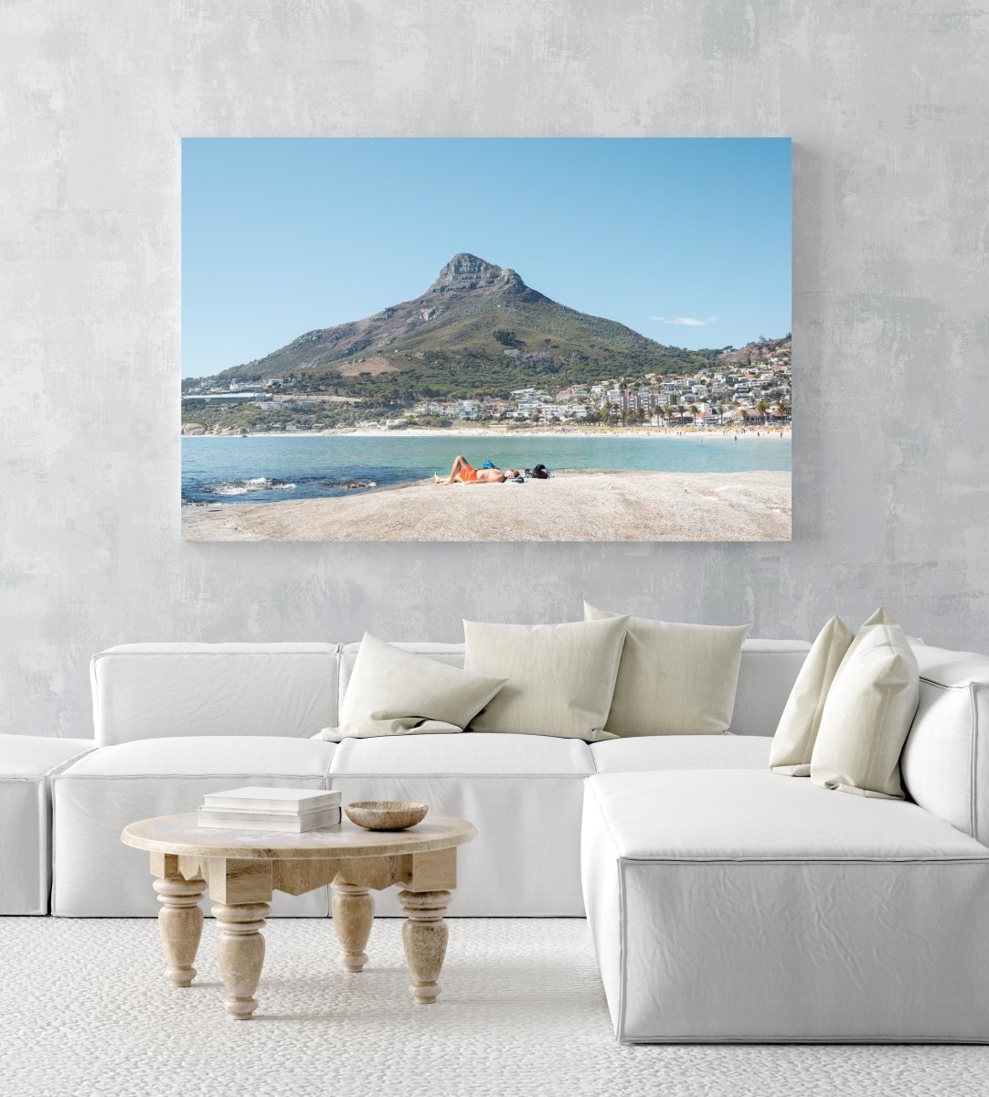 Old man lying on rock at Camps Bay beach below lions head in an acrylic/perspex frame