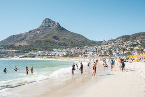 People swimming and playing on Camps Bay Beach below the lions head