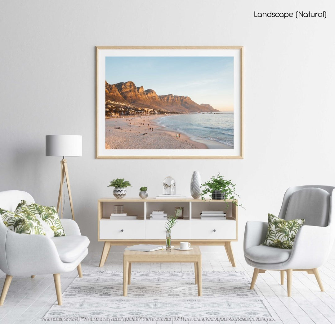 People walking along Camps Bay beach during an orange sunset in a natural fine art frame