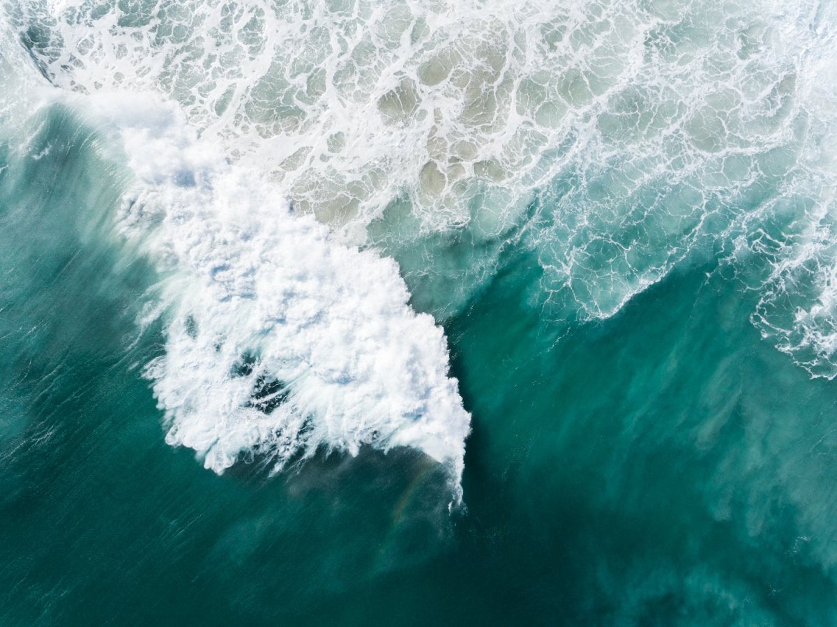 Large wave crashing at Noordhoek beach seen from above