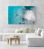 Aerial topdown of girl surfer in wetsuit paddling in blue water in a white fine art frame