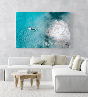 Aerial topdown of girl surfer in wetsuit paddling in blue water in a white fine art frame