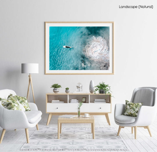 Aerial topdown of girl surfer in wetsuit paddling in blue water in a natural fine art frame