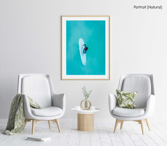 Aerial of girl holding striped surfboard in blue water in Camps Bay Beach in a natural fine art frame