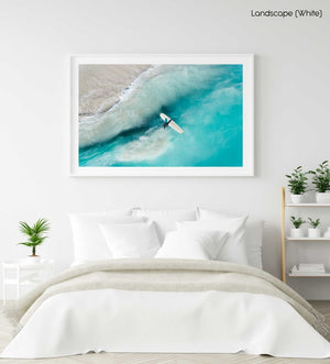 Girl walking back to shore with surfboard in blue water and waves in a white fine art frame