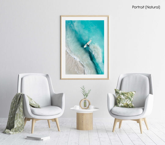 Girl walking back to shore with surfboard in blue water and waves in a natural fine art frame