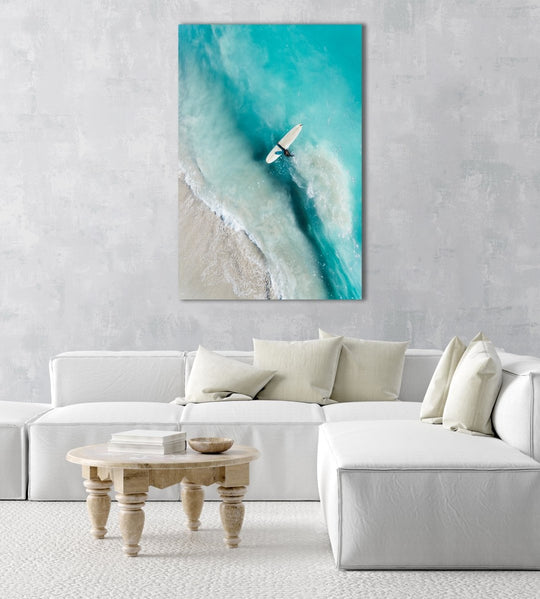 Girl walking back to shore with surfboard in blue water and waves in a natural fine art frame