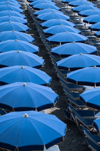 Blue umbrellas and beach chairs lined up in Italy