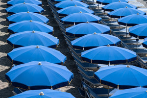 Rows of blue umbrellas and chairs on italian beach