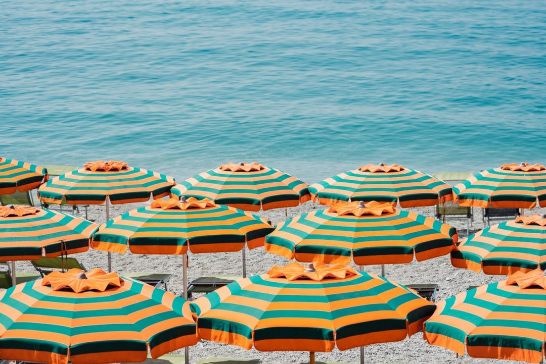 Rows of striped orange umbrellas and turquoise sea in Cinque Terre