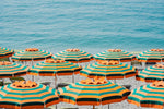 Rows of striped orange umbrellas and turquoise sea in Cinque Terre