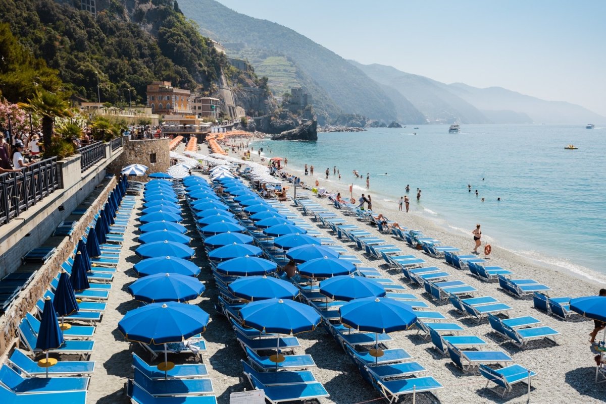 Rows of blue umbrellas along blue mediterranean sea in Cinque Terre