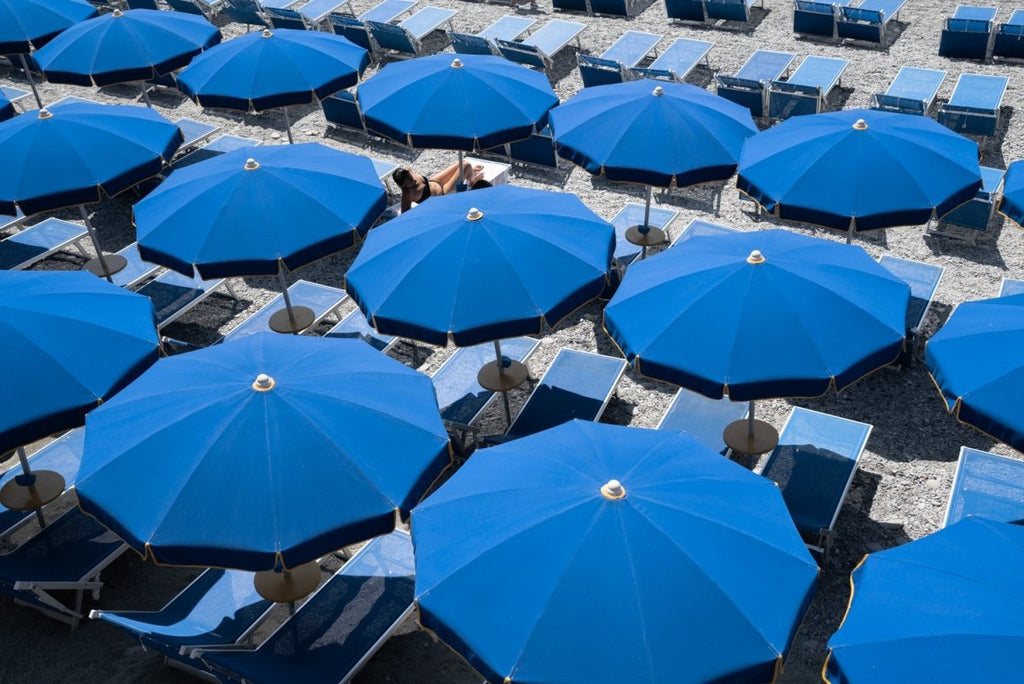 Woman lying under blue umbrellas seen from above