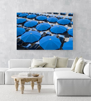 Woman lying under blue umbrellas seen from above in an acrylic/perspex frame