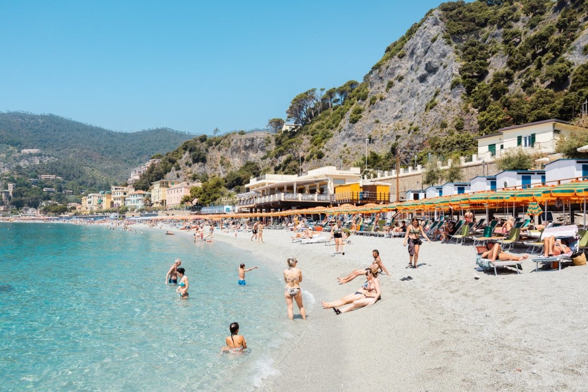 People swimming and sitting at colorful Monterosso beach in Cinque Terre
