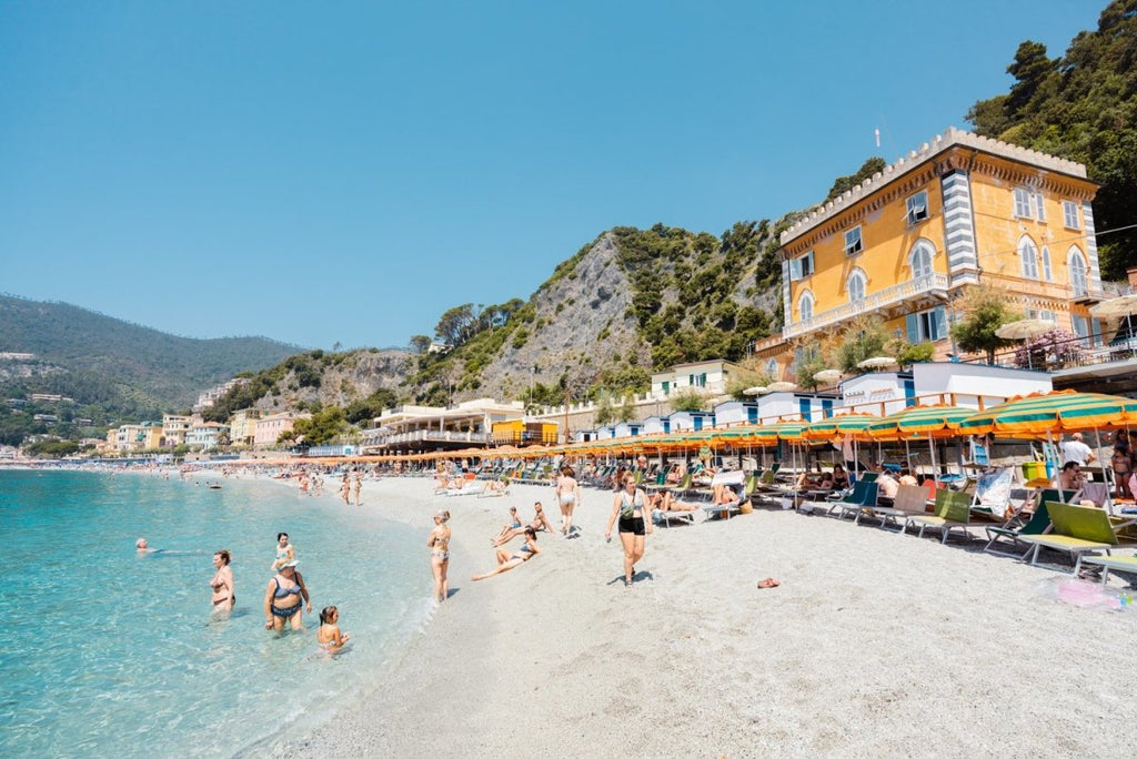 People swimming and sitting at colorful Monterosso beach in Italy