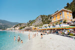 People swimming and sitting at colorful Monterosso beach in Italy