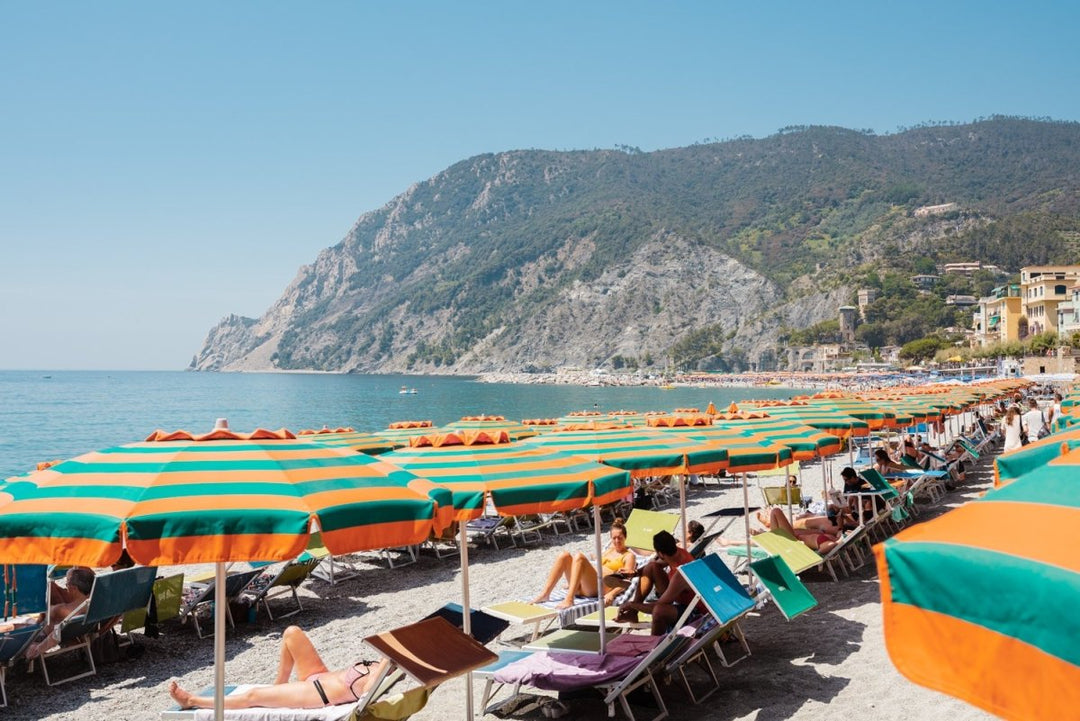 Orange umbrellas and people tanning on Monterosso Beach Cinque Terre