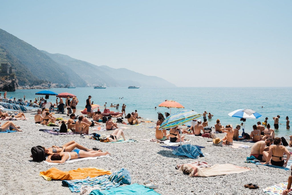 People lying on towels in the sun on Monterosso beach in Cinque Terre