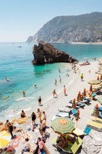 Big rock on Monterosso beach surrounded by people and blue water in Italy