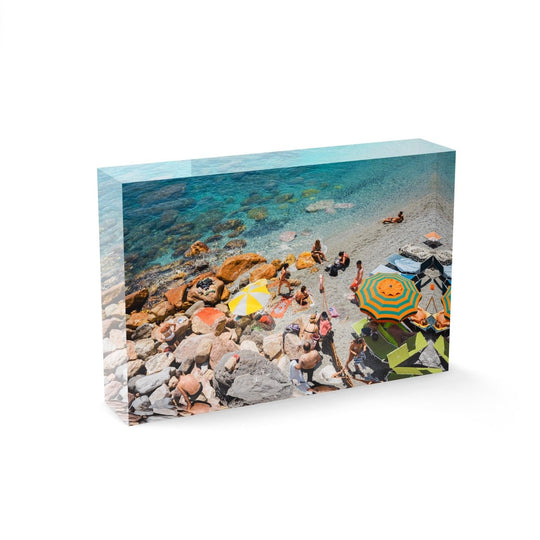 Umbrellas and people on beach with rocks and sand in Cinque Terre