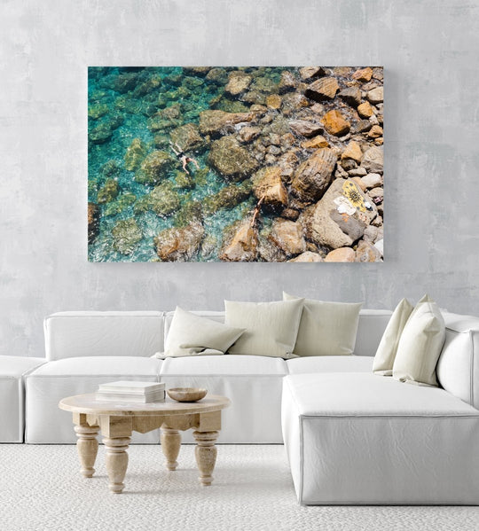 Two people swimming in clear blue water in Cinque Terre in an acrylic/perspex frame