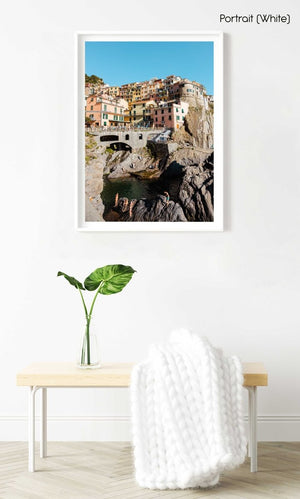 People swimming amongst bridge and colorful buildings of Manarola in Cinque Terre in a white fine art frame