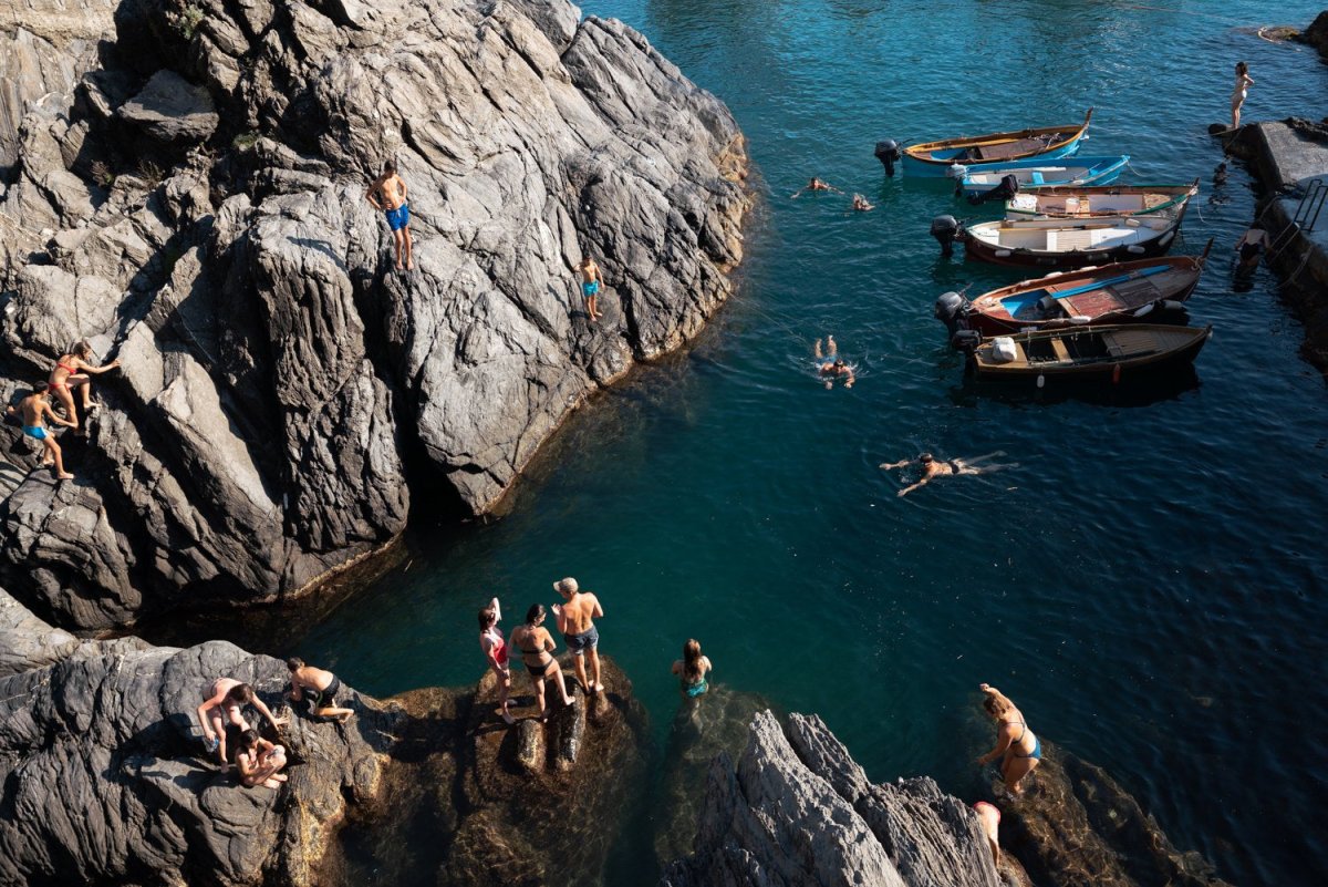 People swimming along dark rocks in Manarola Cinque Terre