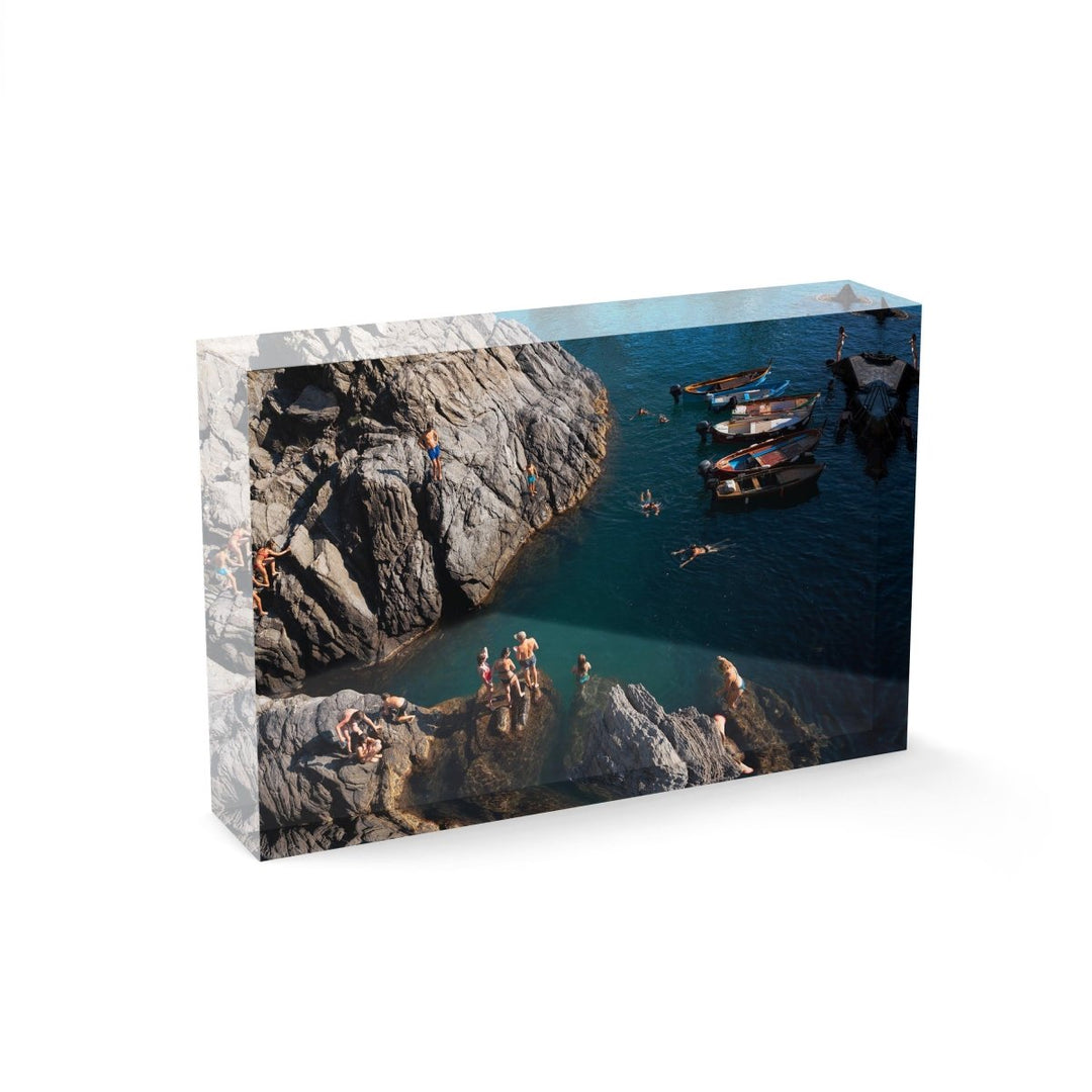 People swimming along dark rocks in Manarola Cinque Terre