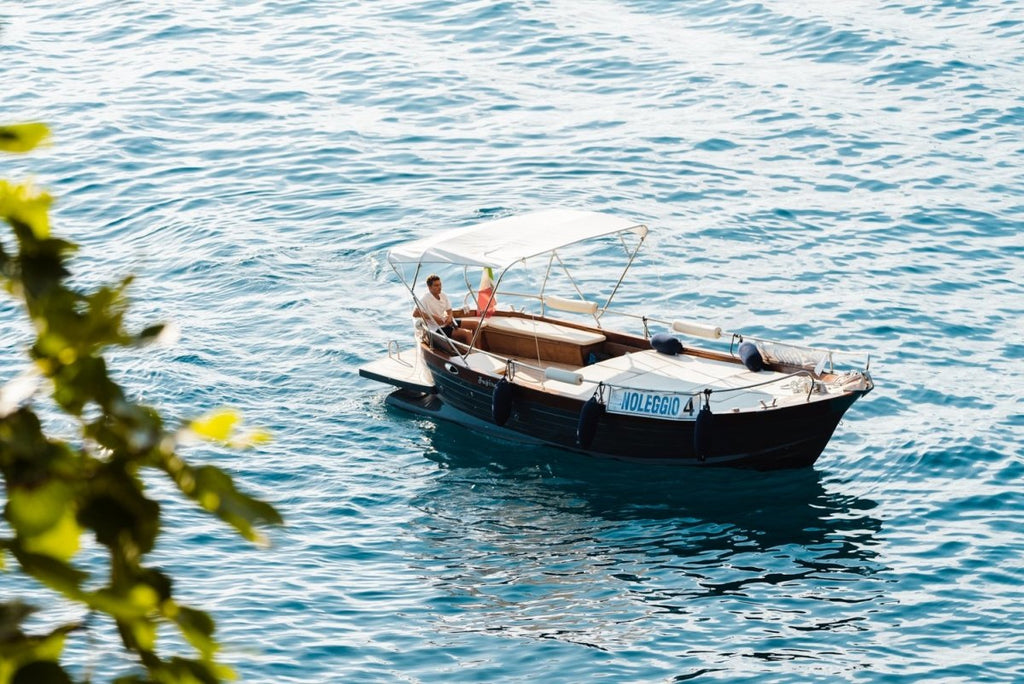 Man driving a rental boat along Cinque Terre coastline