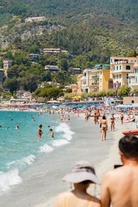 People walking and swimming in blue water of Monterosso beach in Cinque Terre