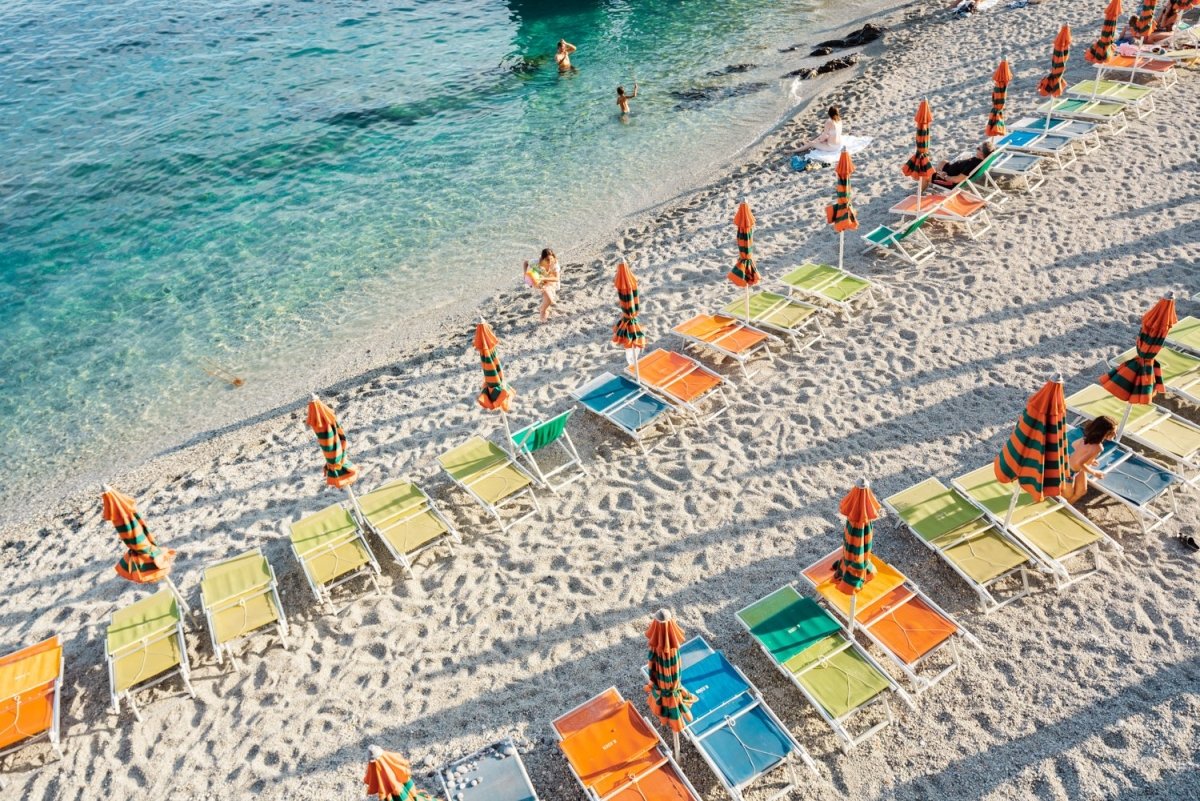 Orange, green and blue chairs on beach in Cinque Terre