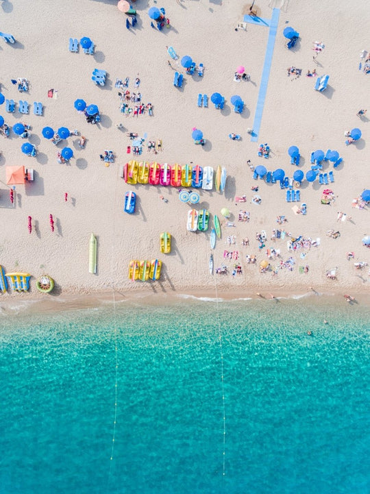 Colorful umbrellas, boats and water seen from air above Lloret de Mar beach