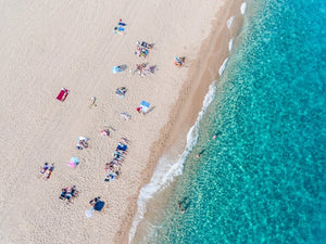 Simplistic aerial of blue ocean and people sunbathing in Costa Brava