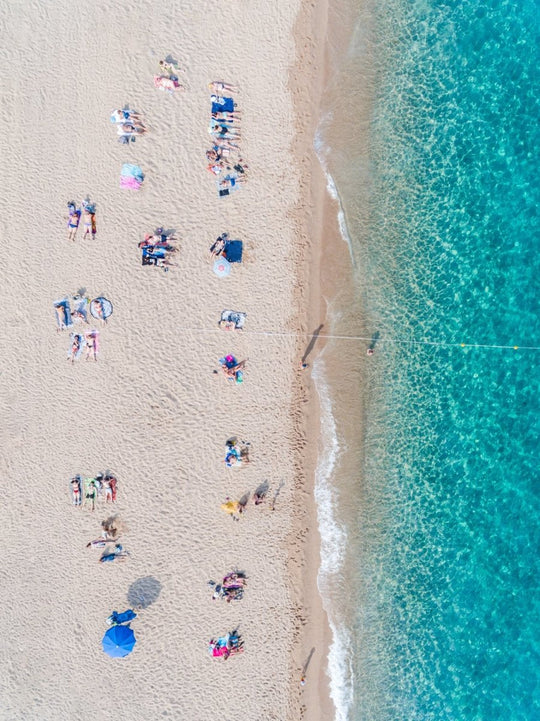 Lines of people tanning on beach in Spain from aerial view