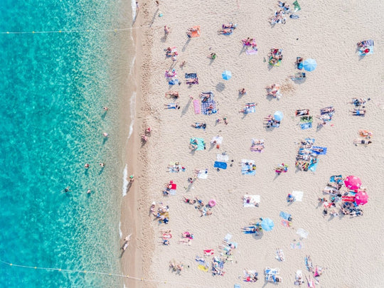 Topdown view of people lying on beach with bright blue water in Costa Brava