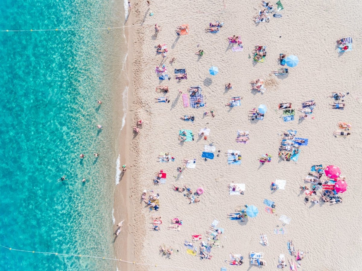 Topdown view of people lying on beach with bright blue water in Costa Brava