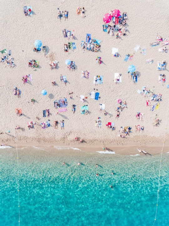 Topdown view of people lying on beach with bright blue water in Costa Brava