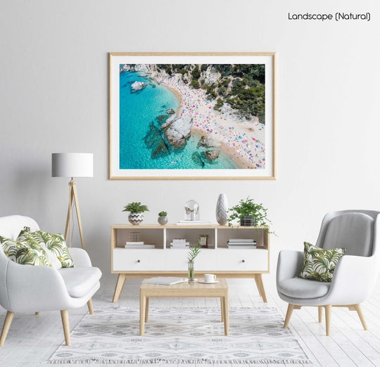 Aerial of bright blue sea, colorful umbrellas and people at Cala sa Boadella beach in a natural fine art frame